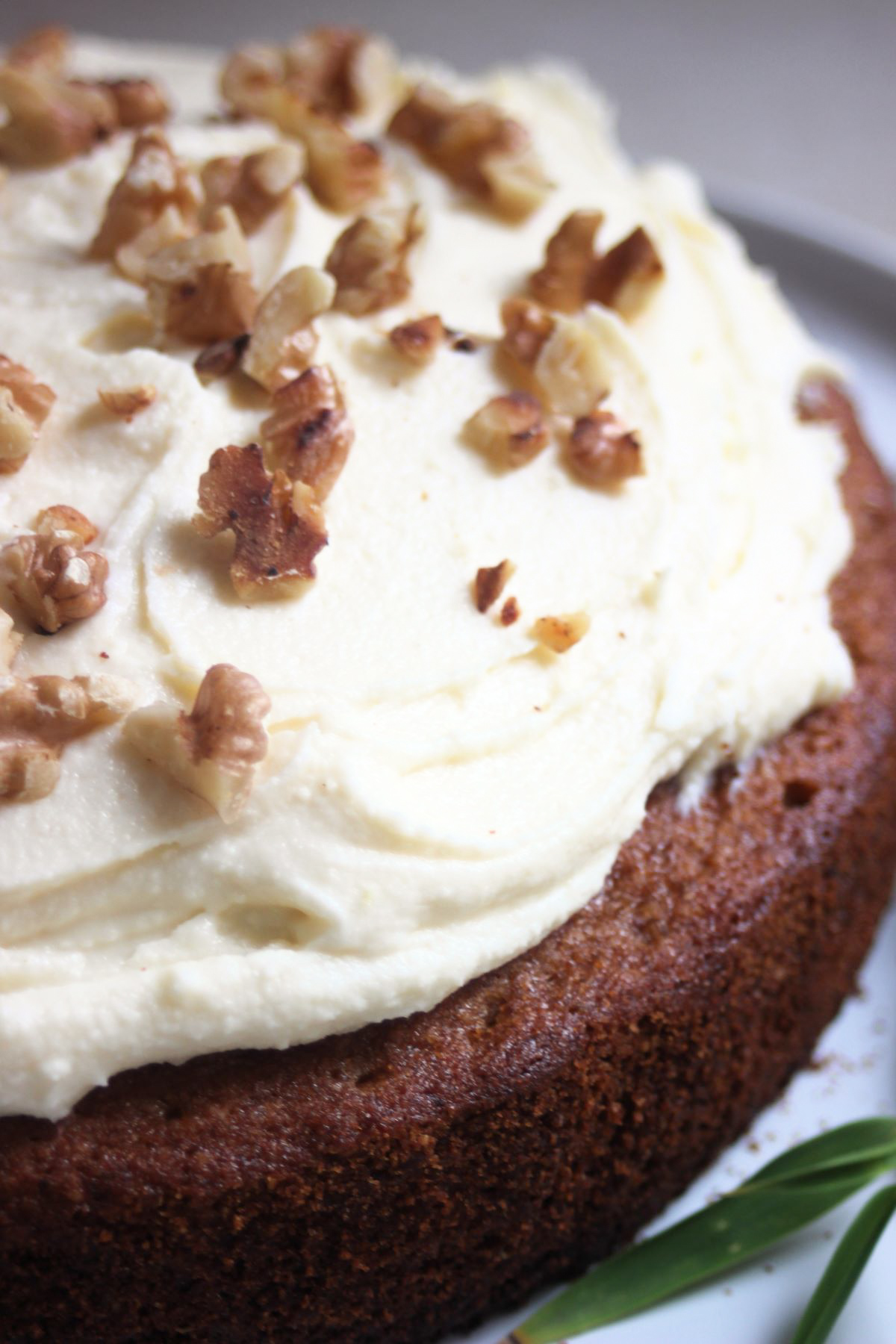 Closer view of a sweet potato cake with cream cheese frosting and chopped walnuts.