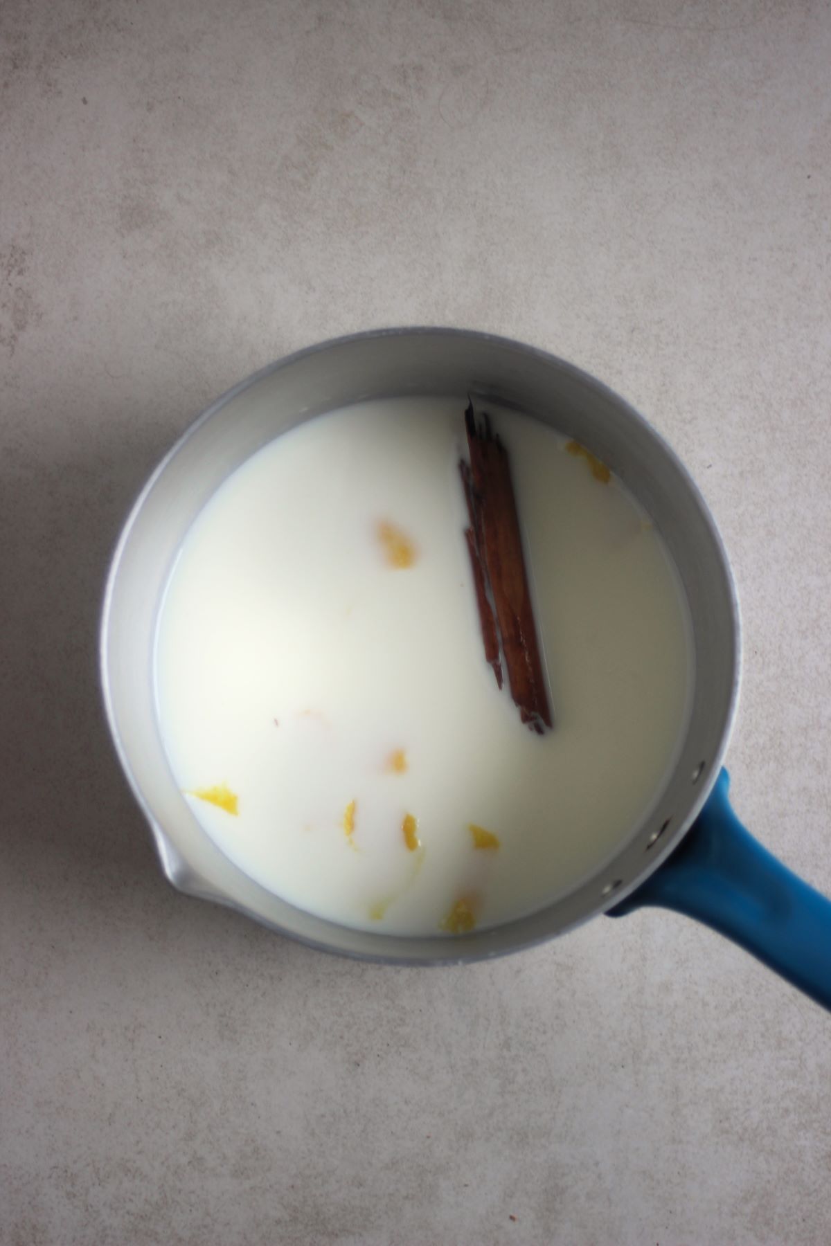 Deep saucepan with milk, cinnamon stick, and lemon rind.