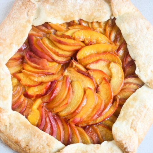 Peach galette on a white surface seen from above.