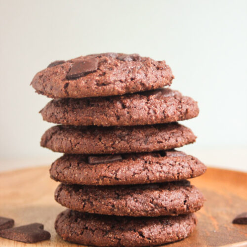 A tower of chocolate cookies on a wooden plate.