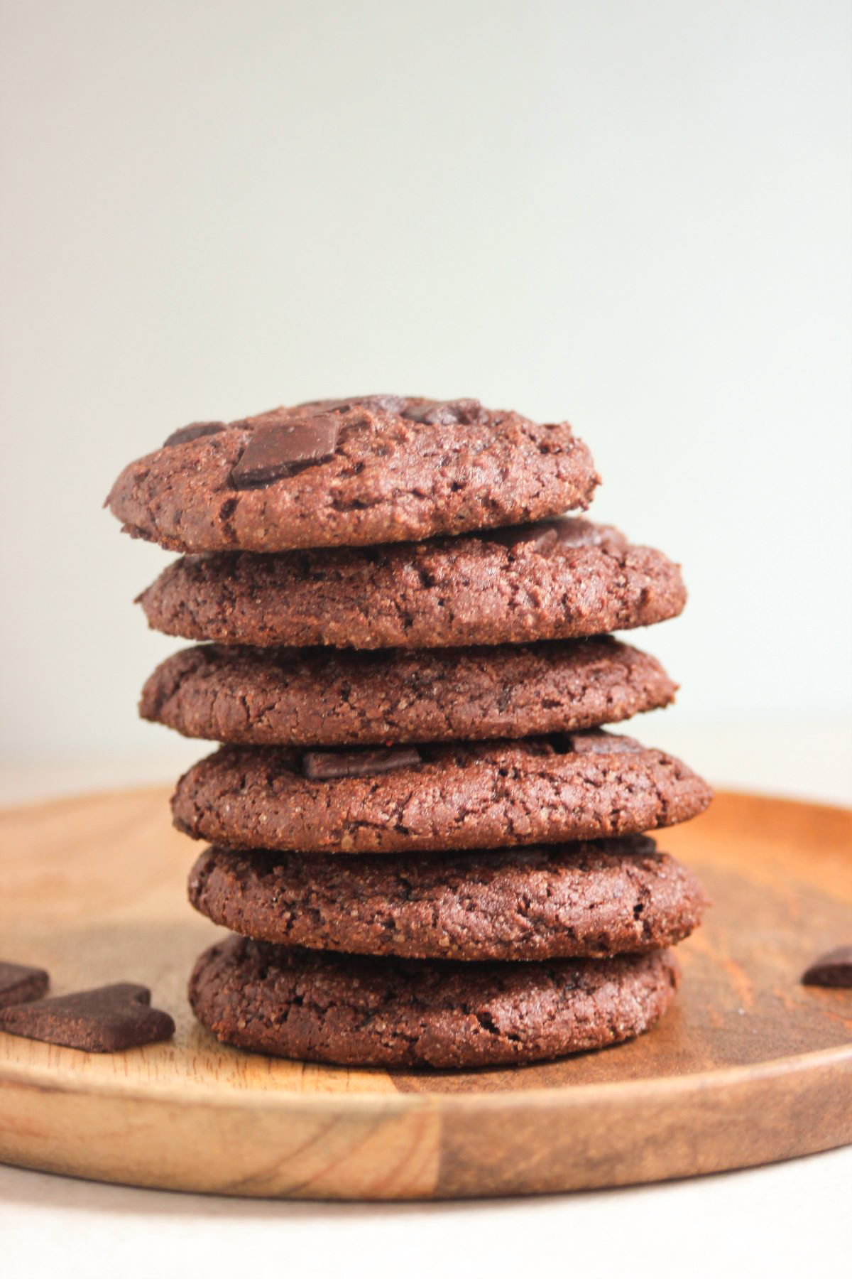 A tower of chocolate cookies on a wooden plate.