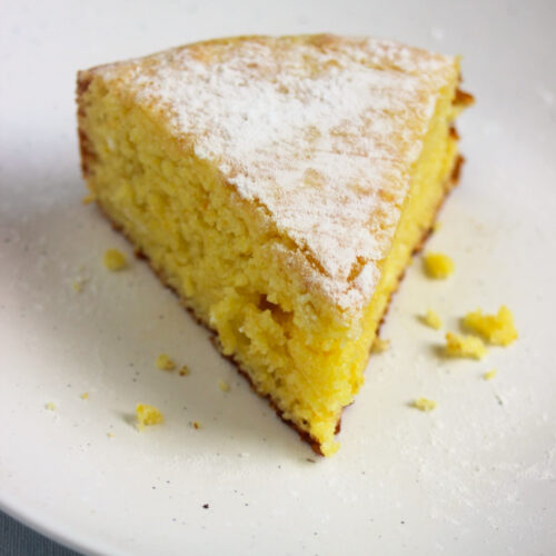 A portion of orange cake on white plate.