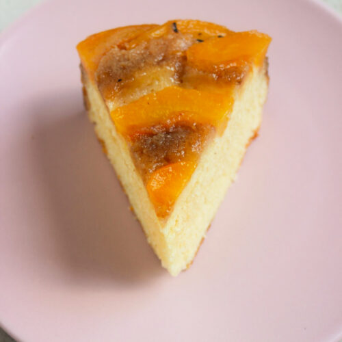 A portion of peach upside down cake on a pink plate,