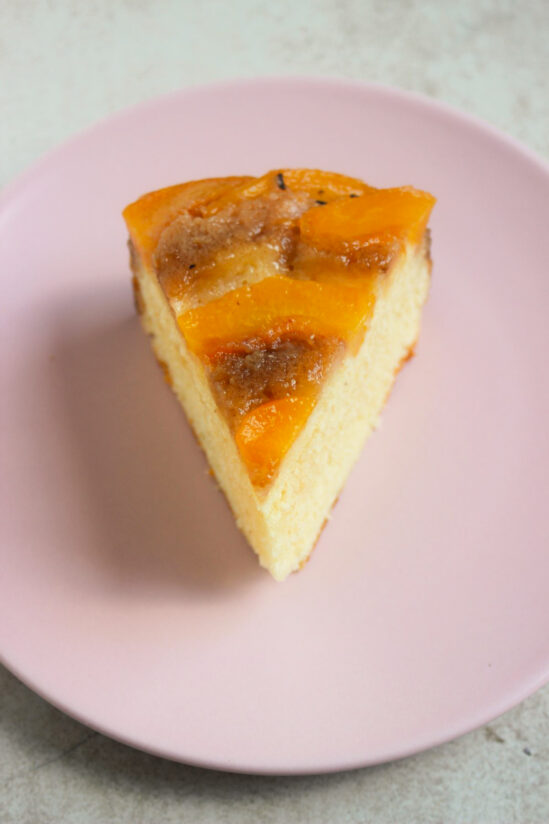 A portion of peach upside down cake on a pink plate,