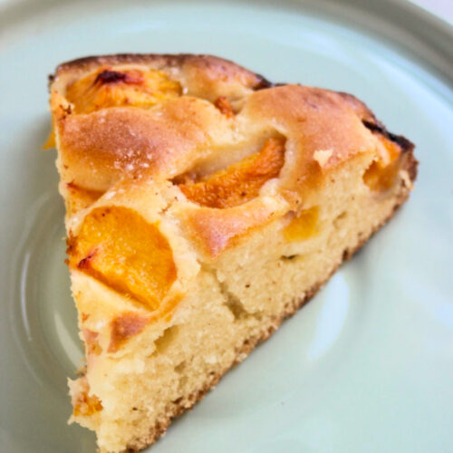 A portion of peach cake on an aqua green plate.