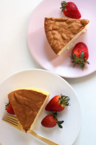 Two plate with a portions of japanese cheesecake and fresh strawberries seen from above.