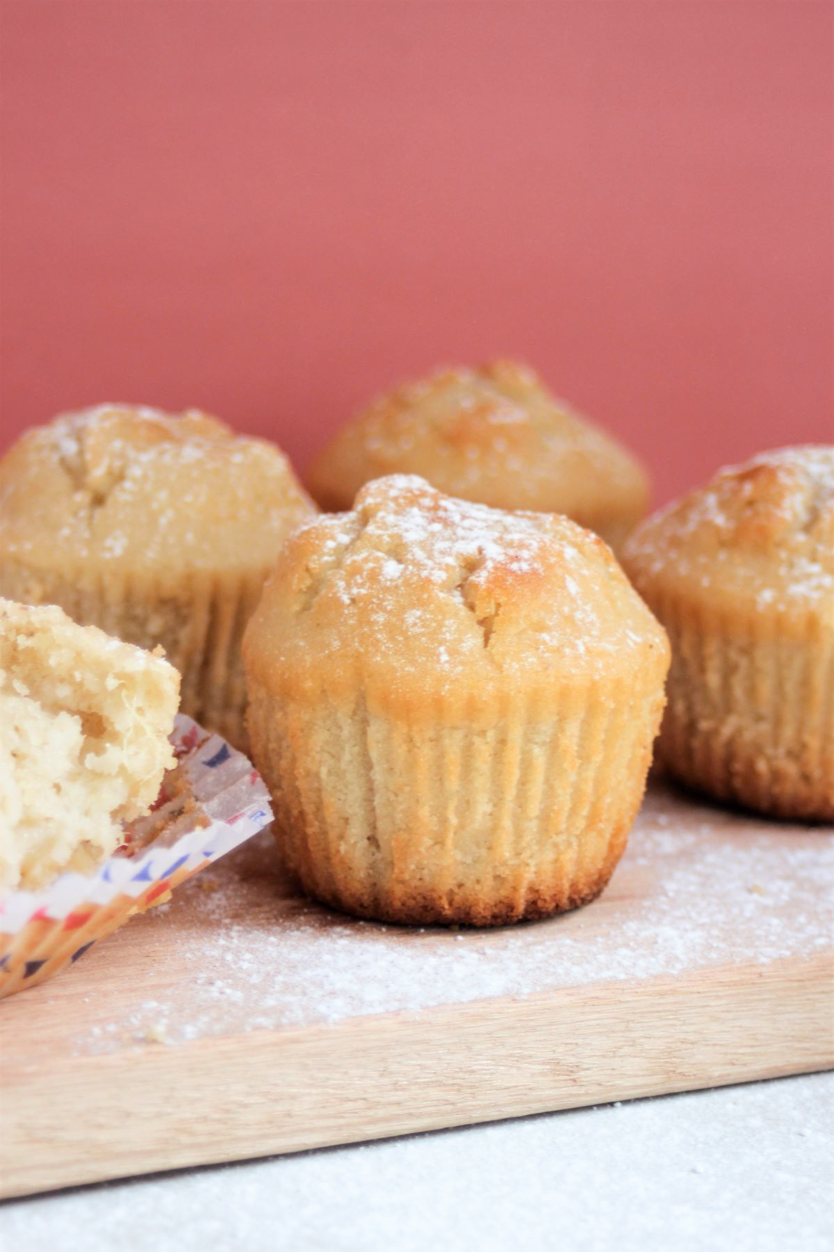 Pear and ginger muffins on a wood board. Pink background.