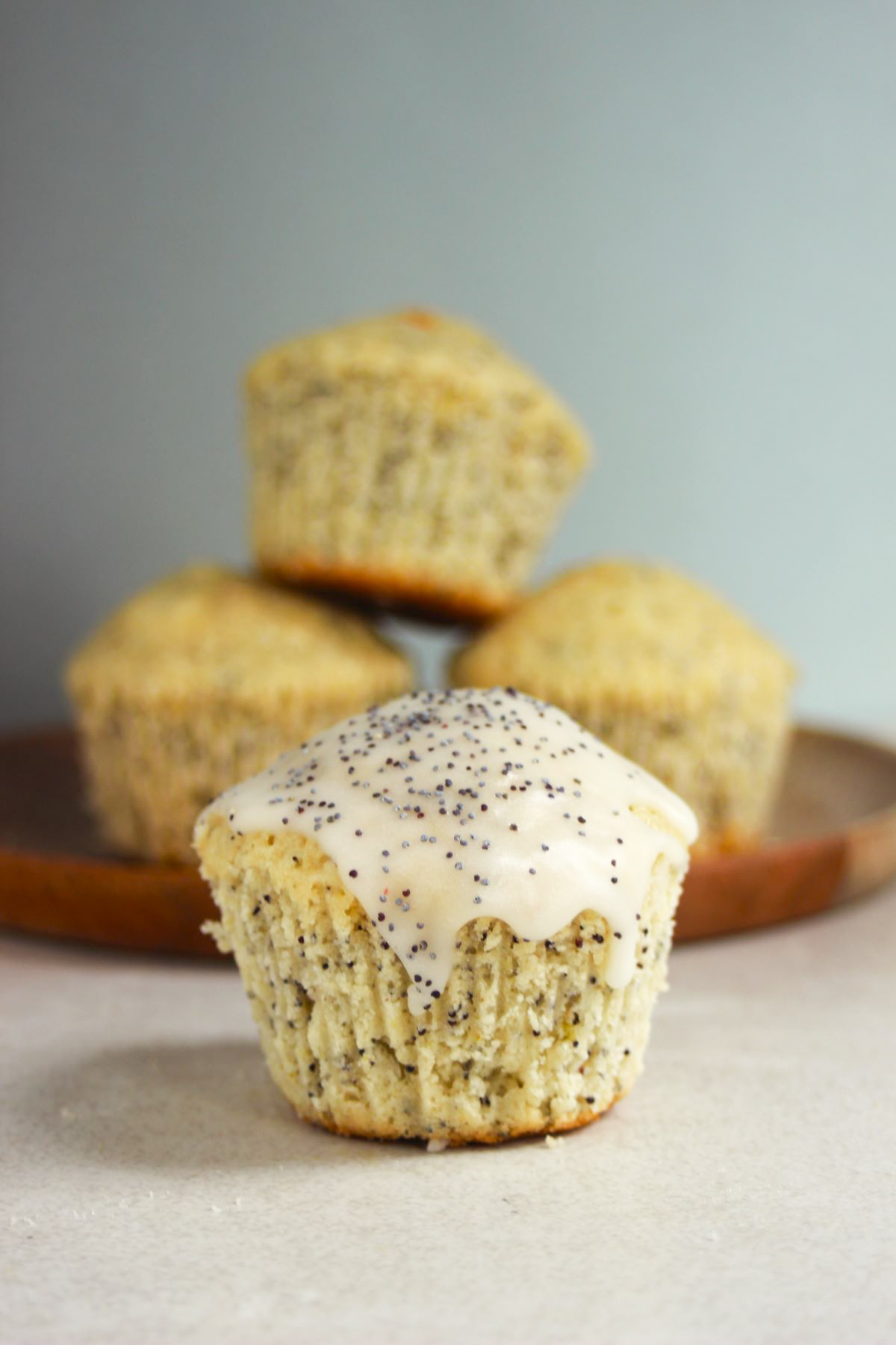 Lemon muffin with icing and poppy seeds. More muffins behind.