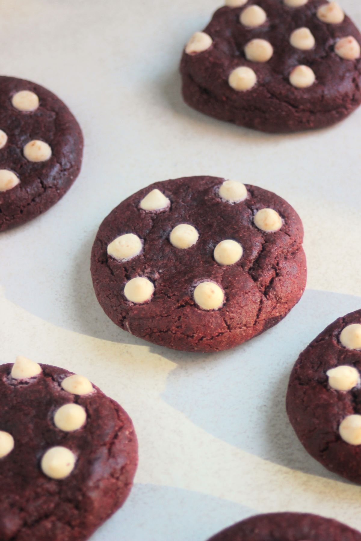 Red velvet cookies with white chocolate chips on a white surface.