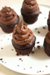 Chocolate cupacakes with cocoa nibs on a white plate.