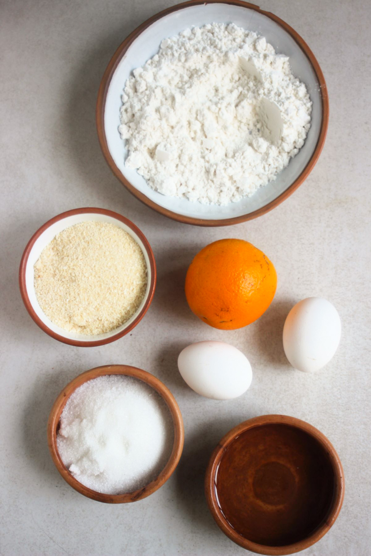 Orange coconut muffins ingredients on a white surface seen from above.