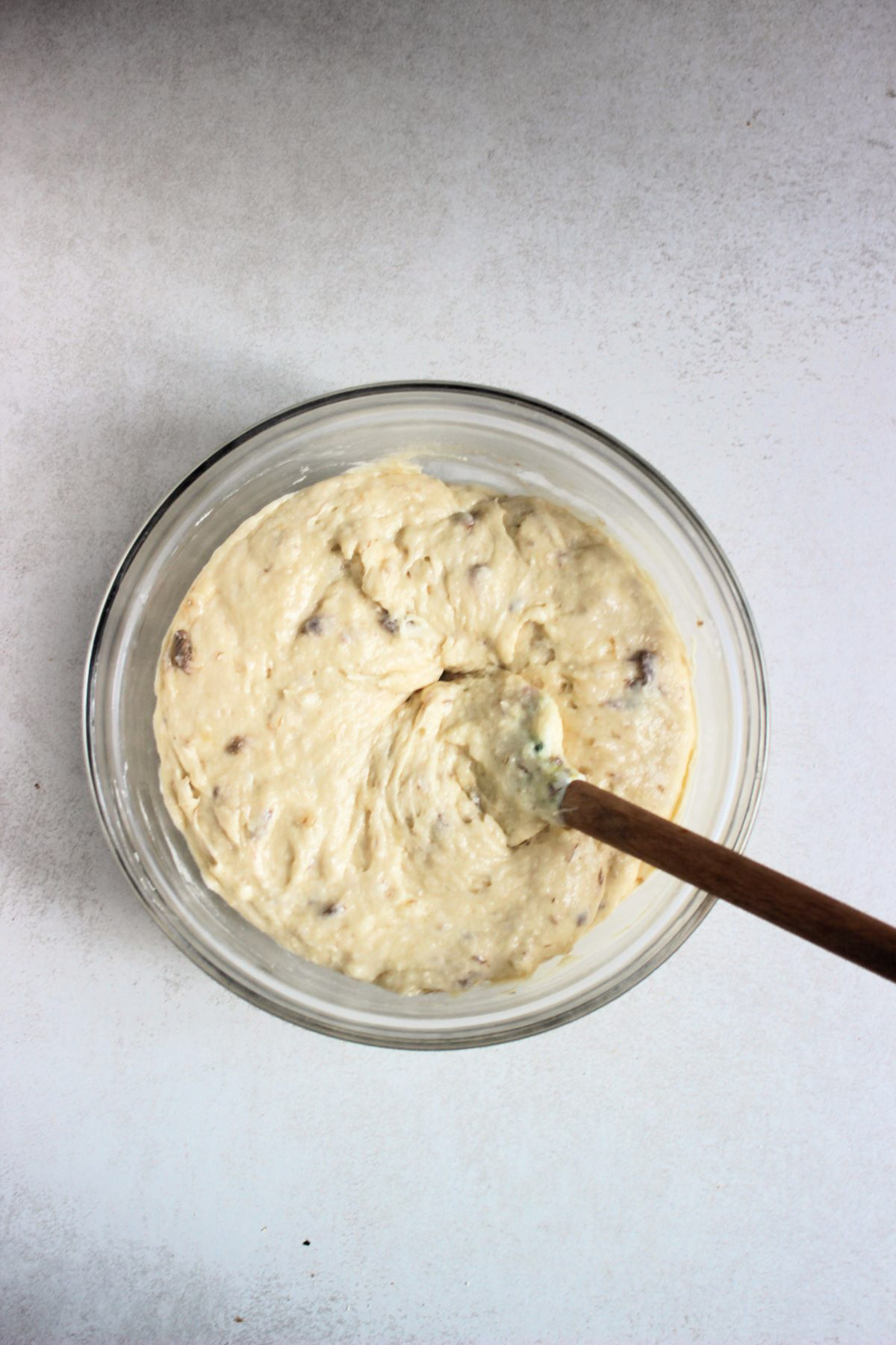 A glass bowl with a smooth cream colour mixture and a spatula.