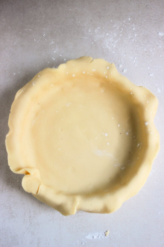 Raw pie dough on a baking dish seen from above.