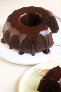 Chocolate Bundt Cake drizzled with chocolate ganache on a white plate.