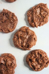 Chocolate brownie cookies on a white surface seen from above.