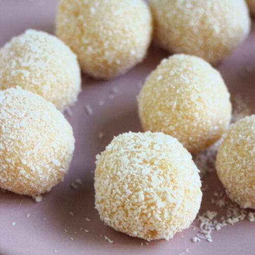 Coconut brigadeiros on a pink plate.