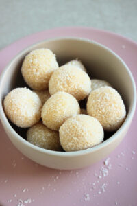 Coconut brigadeiros on a small boel on a pink plate.