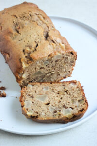 Pear bread and a slice of it on a white plate.