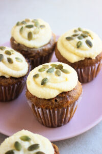 Carrot cake cupcakes with cream cheese frosting on a pink plate.