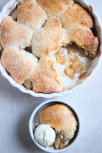 Apple cobbler and a small bowl with a portion of cobbler with a scoop of ice cream seen from above.