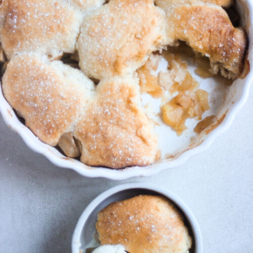 Apple cobbler and a small bowl with a portion of cobbler with a scoop of ice cream seen from above.