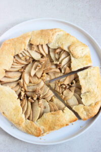 Apple galette on a white plate seen from above. One portion is cut.