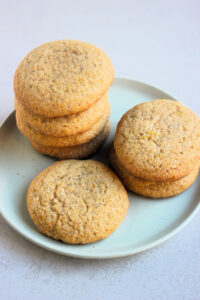 Cornmeal cookies stacks on an aqua-green plate.