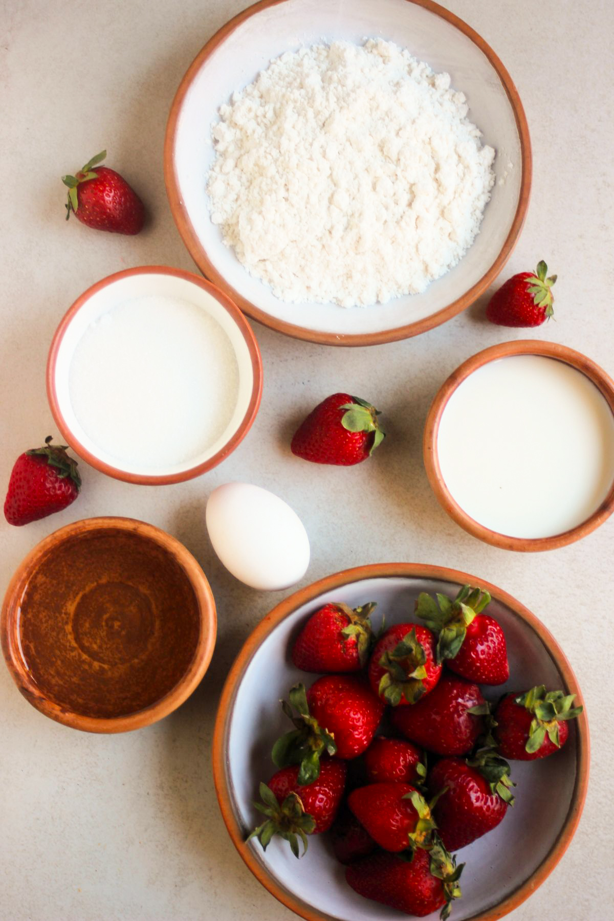Strawberry streusel muffins ingredients on a white surface seen from above.