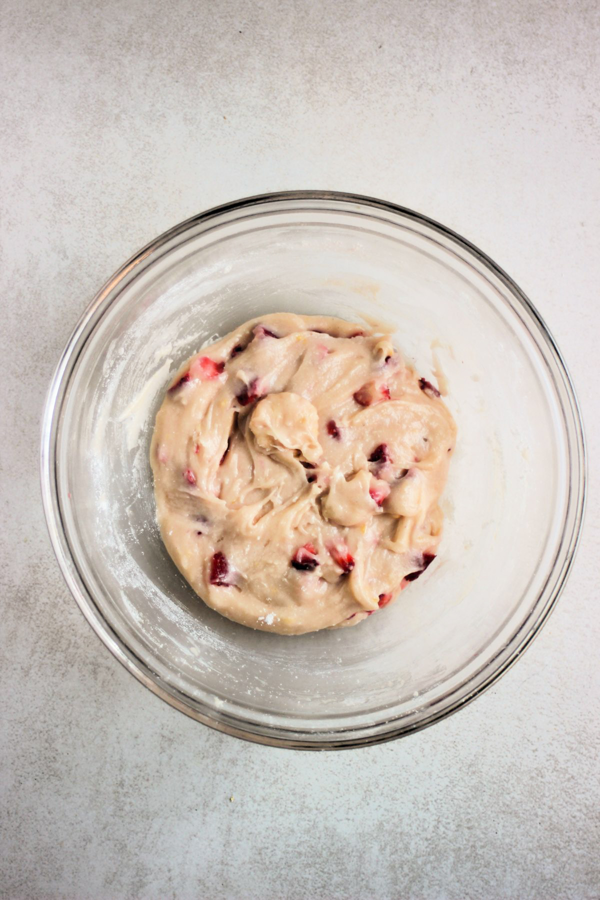 Glass bowl with a smooth and sticky mixture that includes strawberries.