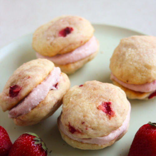 Strawberry whoopie pies and fresh strawberries on an aqua green plate.