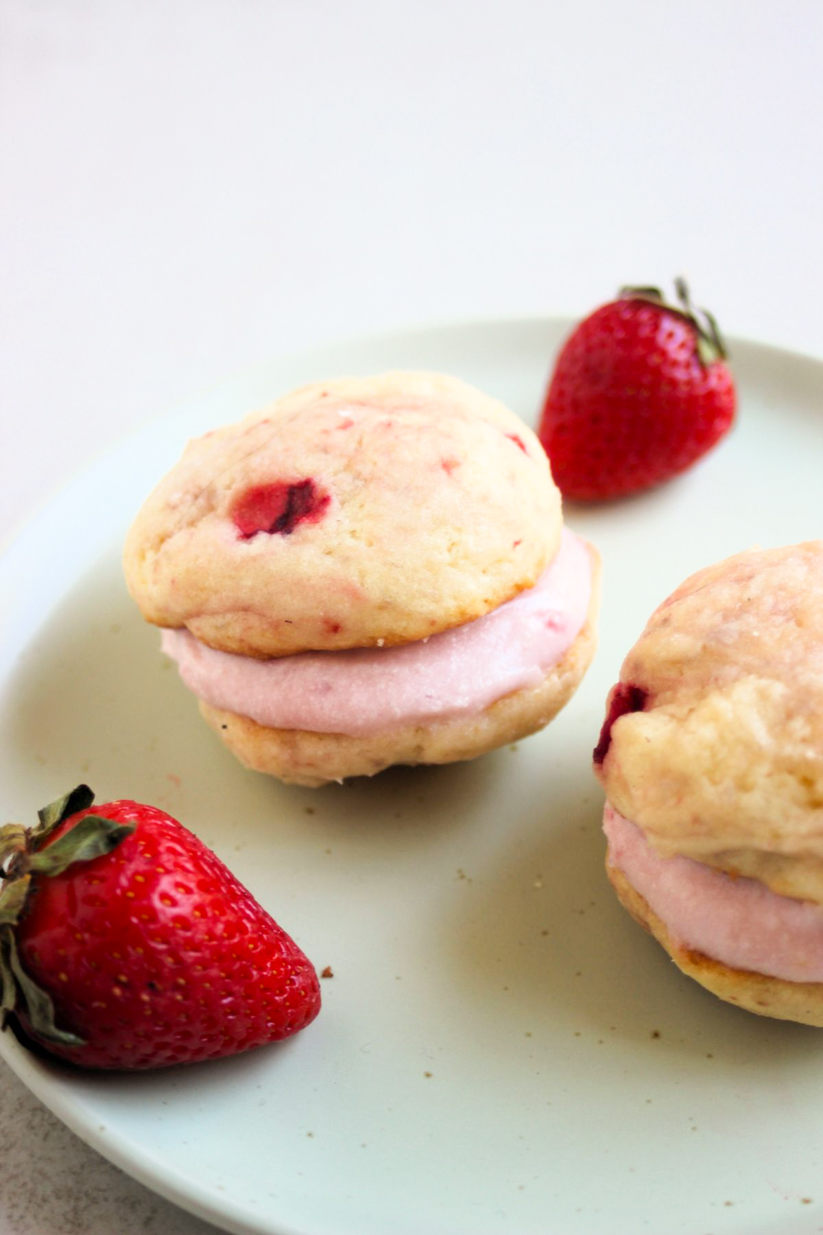 Strawberry whoopie pie and fresh strawberries on an aqua green plate.