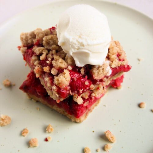 Two strawberry bars, one is above the other, and a scoop of icea cream on top on an aqua green plate.