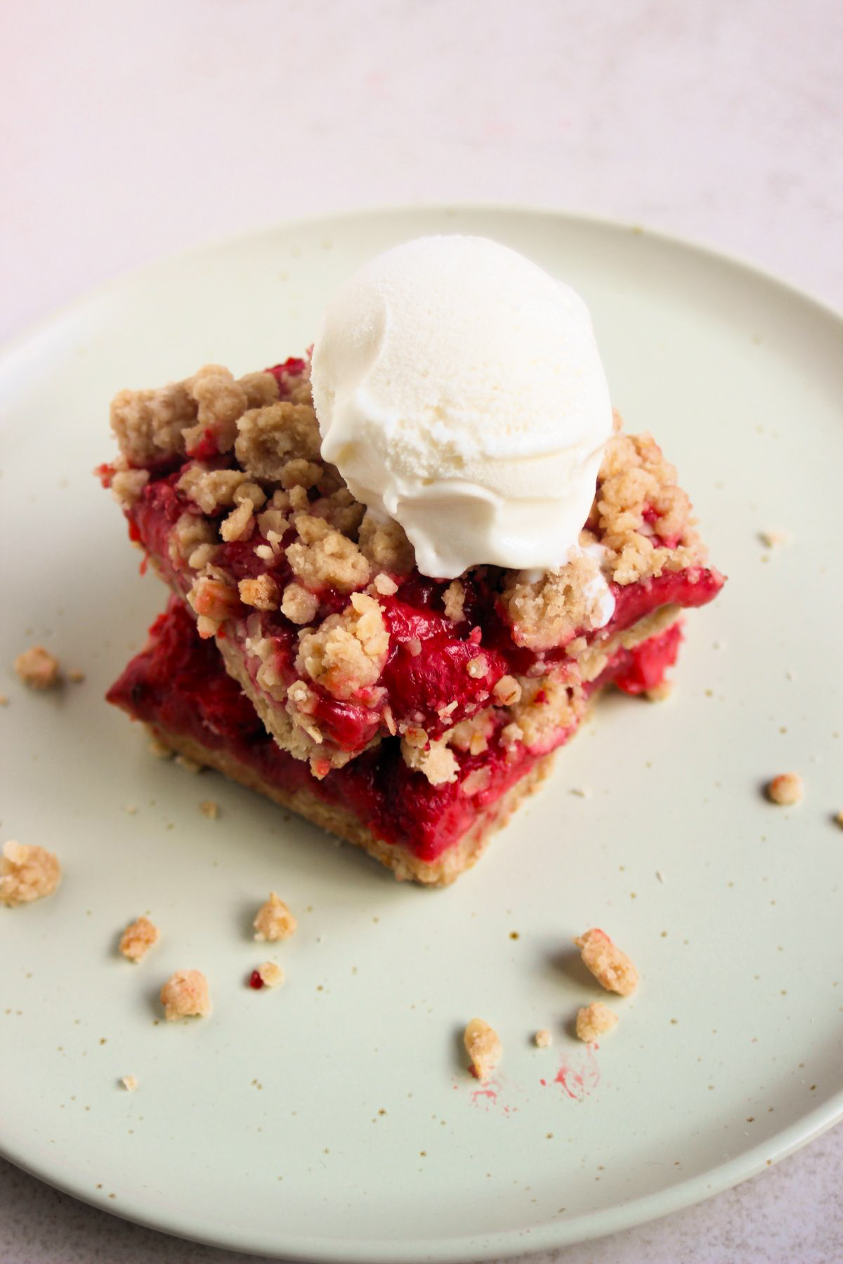 Two strawberry bars, one is above the other, and a scoop of icea cream on top on an aqua green plate.