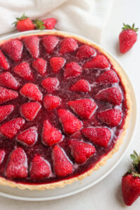 Partial view of strawberry tart. White background, loose strawberries.