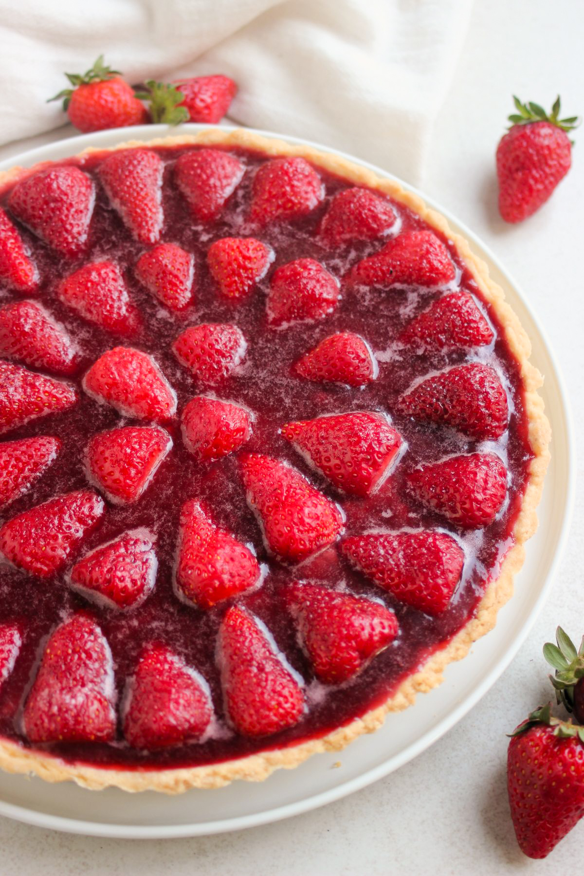 Partial view of strawberry tart. White background, loose strawberries.
