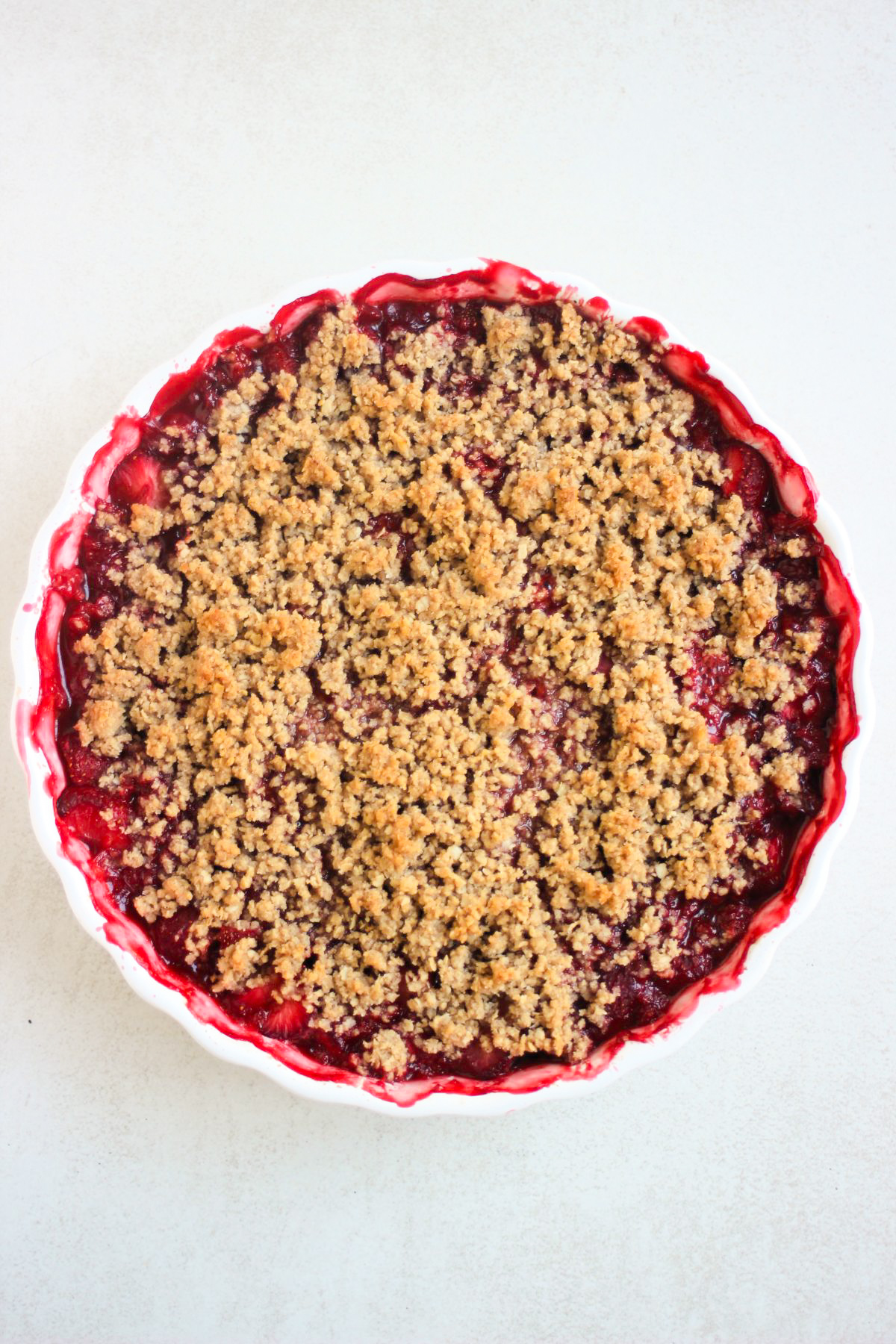 Top view of a round baking dish with strawberry crisp.