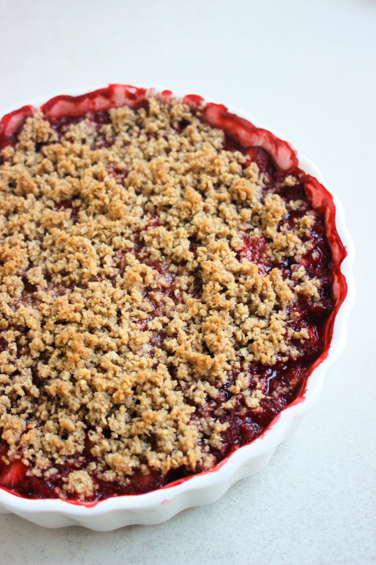 Partial view of a round baking dish with strawberry crisp.
