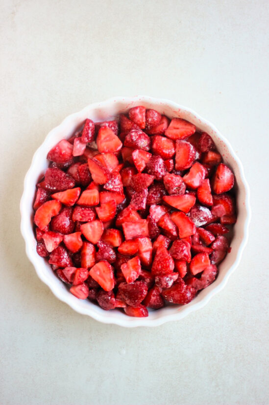 Top view of a round baking dish with fresh chopped strawberries.
