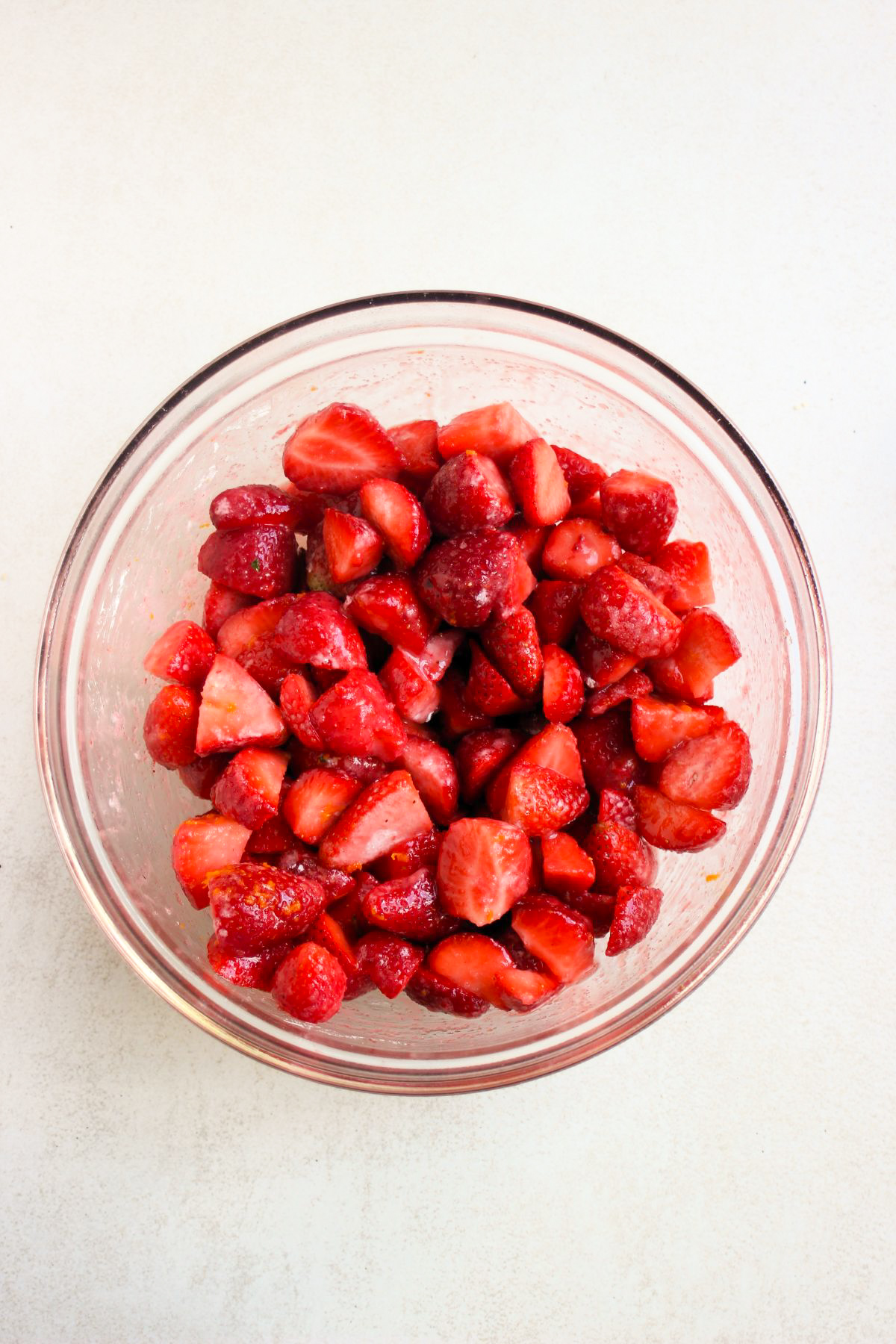 Top view of glass bowl with chopped strawberries.