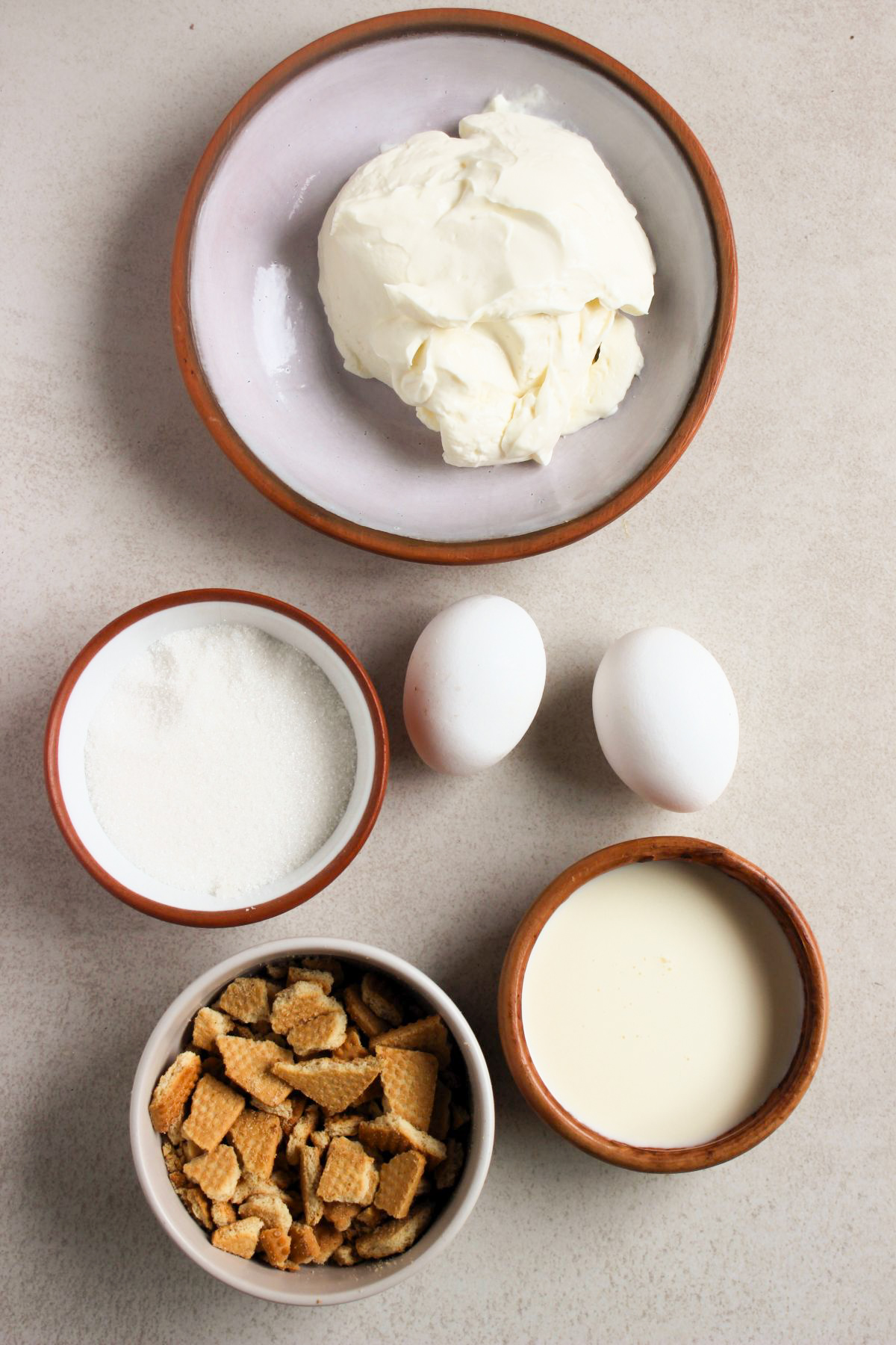 Top view of mini cheesecakes ingredients on a white surface.