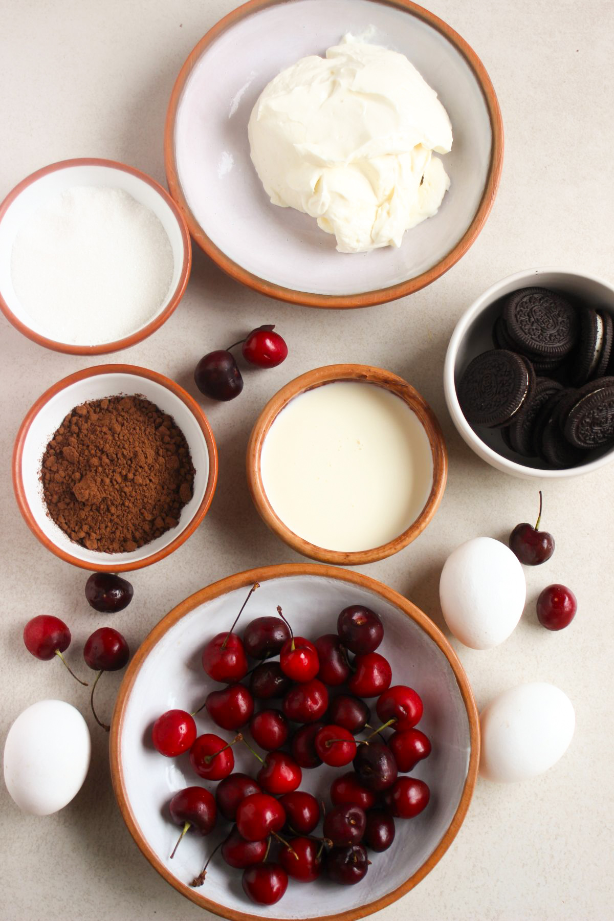 Top view of black forest cheesecake ingredients on a white surface.