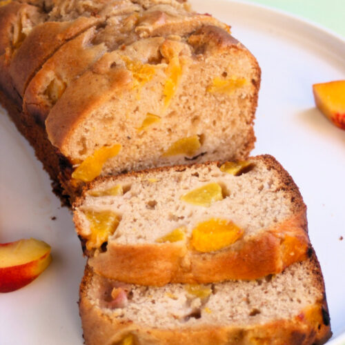 Peach loaf cake and slices of it, on a white plate. Fresh peach slices on the sides.