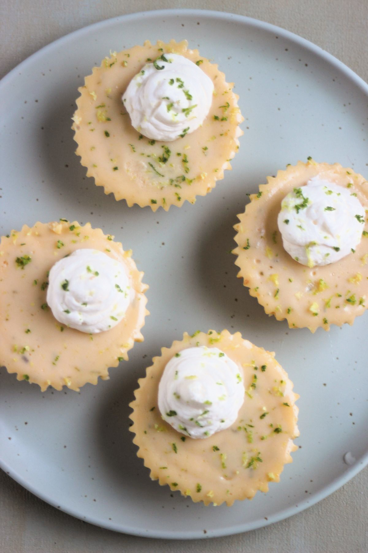 Top view of mini key lime pies with whipped cream on an aqua-green plate.