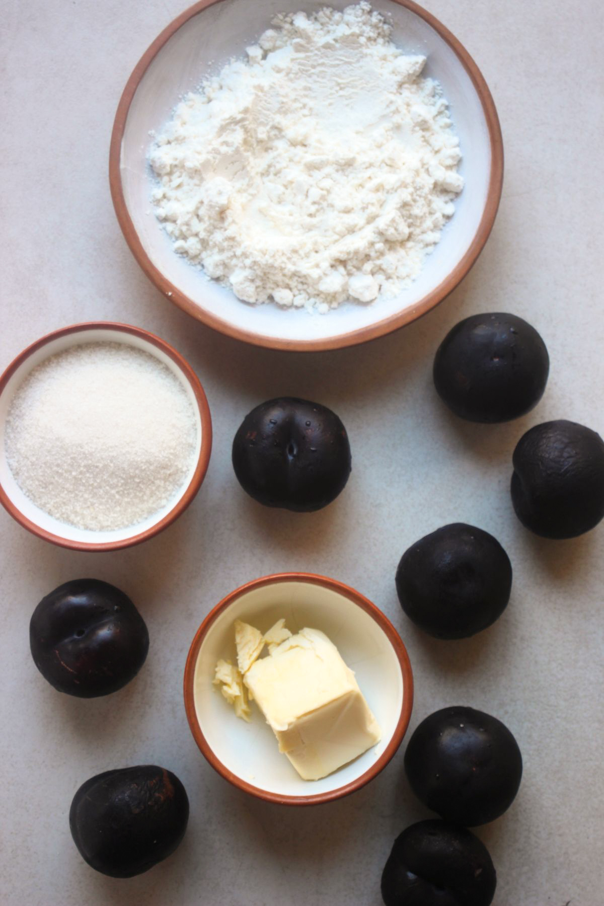 Top view of plum crumble ingredients on a white surface.