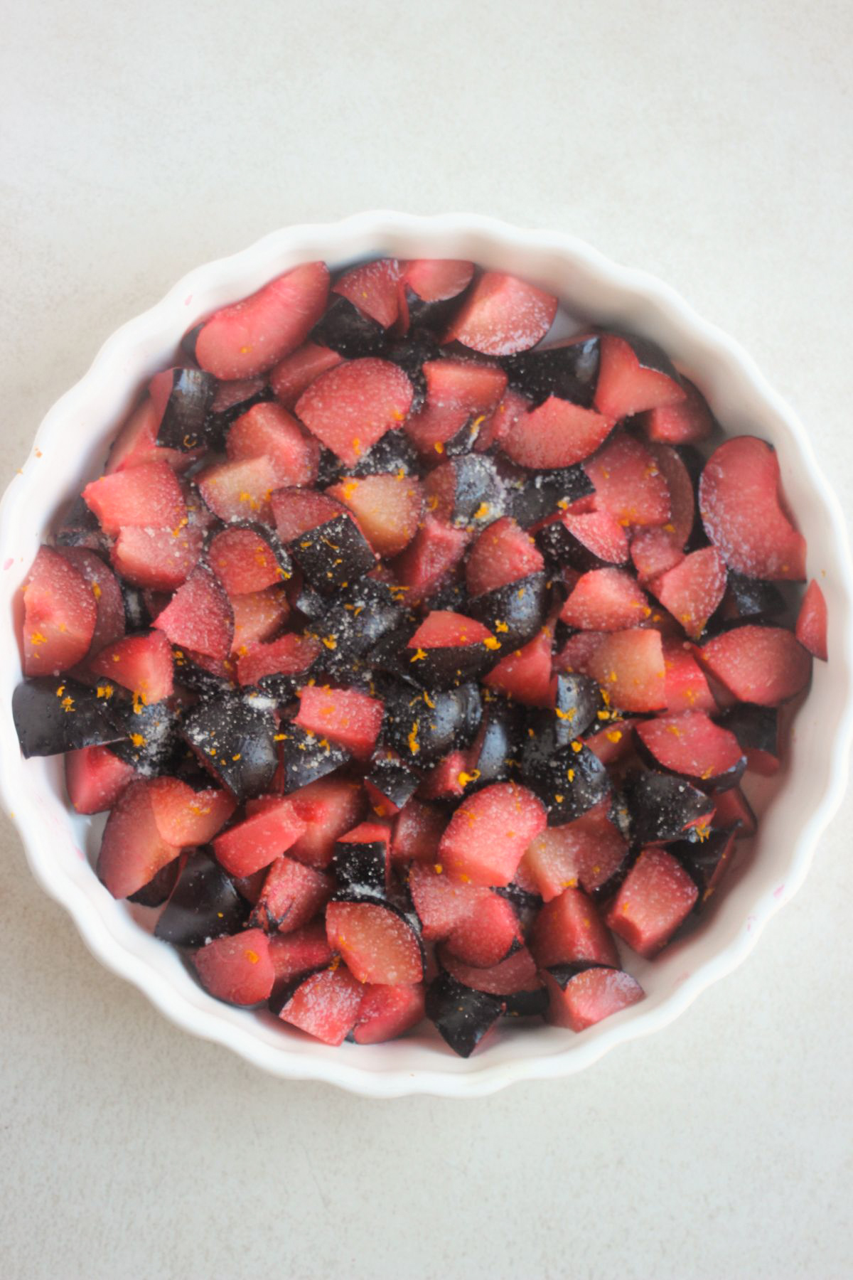 Top view of a round baking dish with fresh sliced plums.
