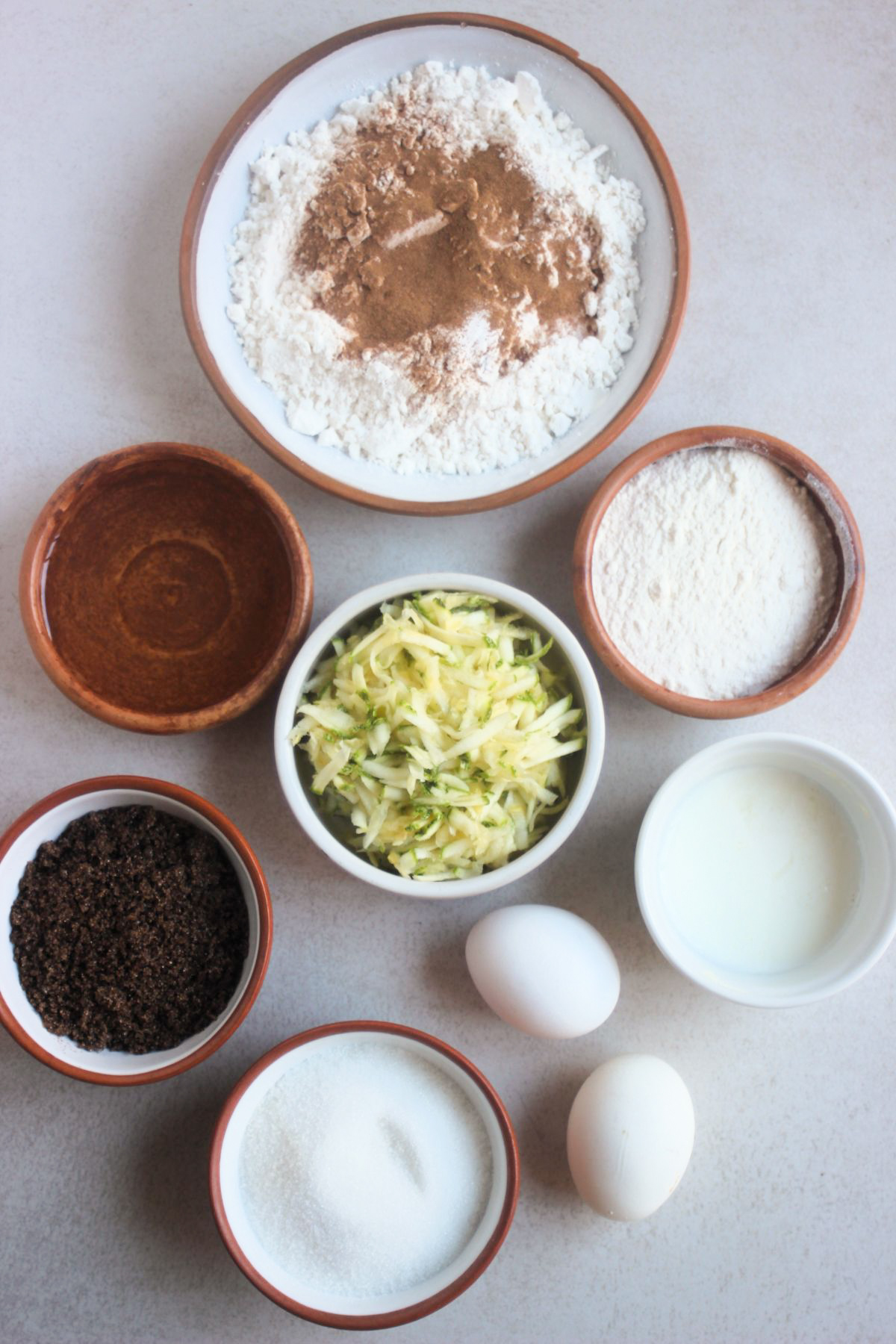 Top view of zucchini bread ingredients on a white surface.