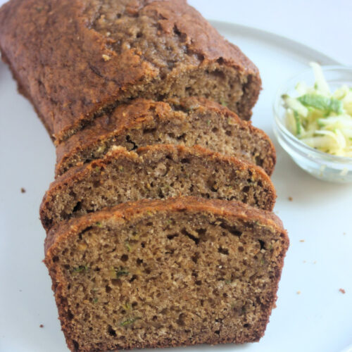 Front view of sliced zucchini bread on a white plate.