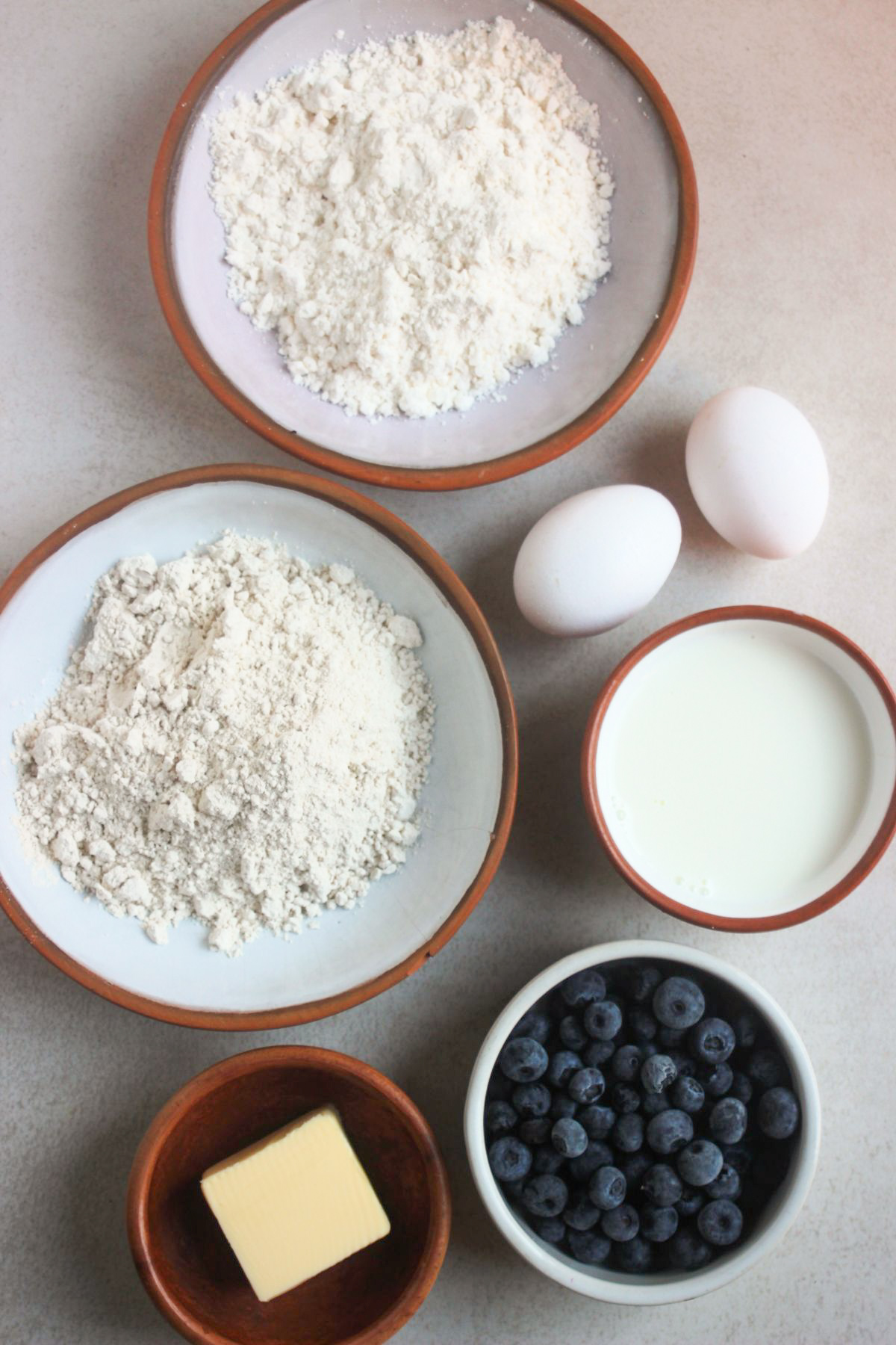 Top view of blueberry pancakes ingredients on a white surface.