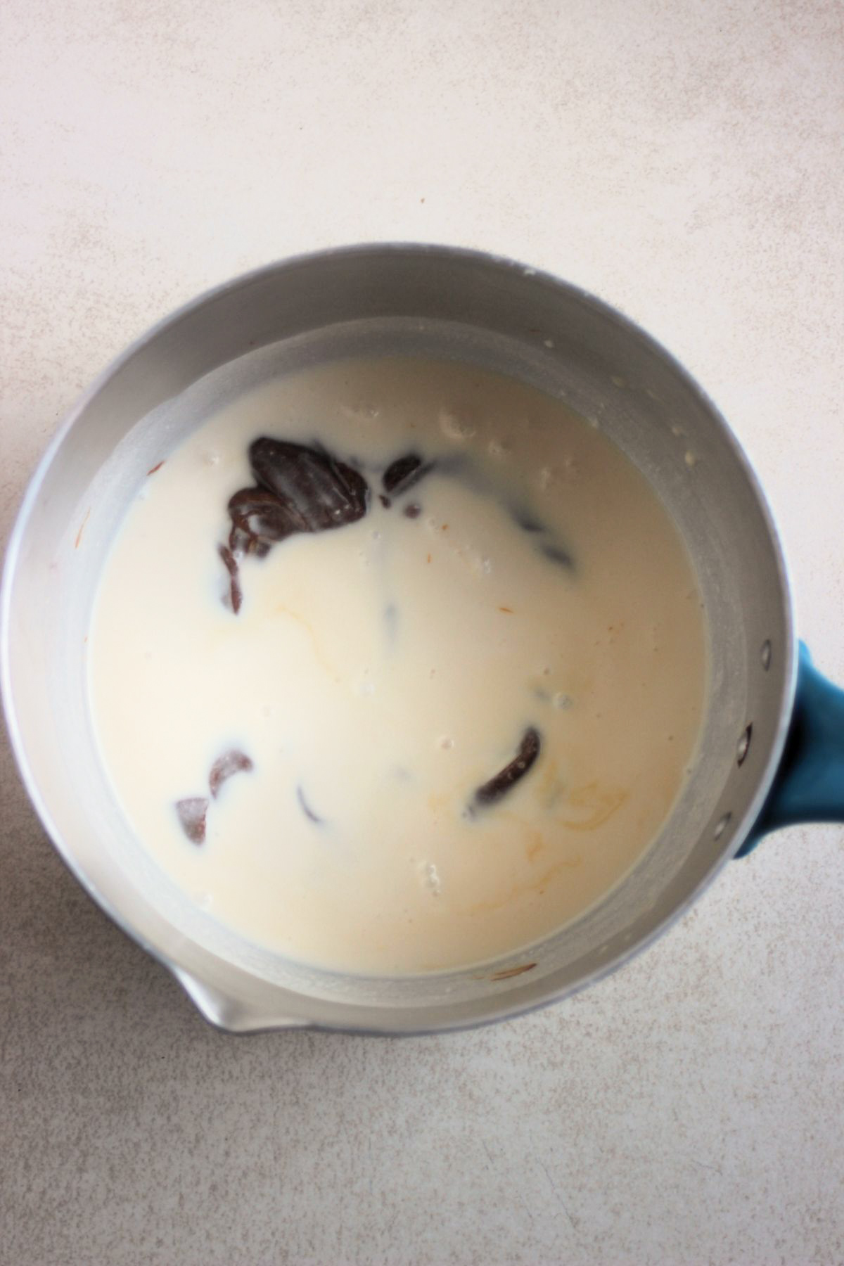 Top view of the inside of a deep saucepan that includes a milk, cream, and dulce de leche.
