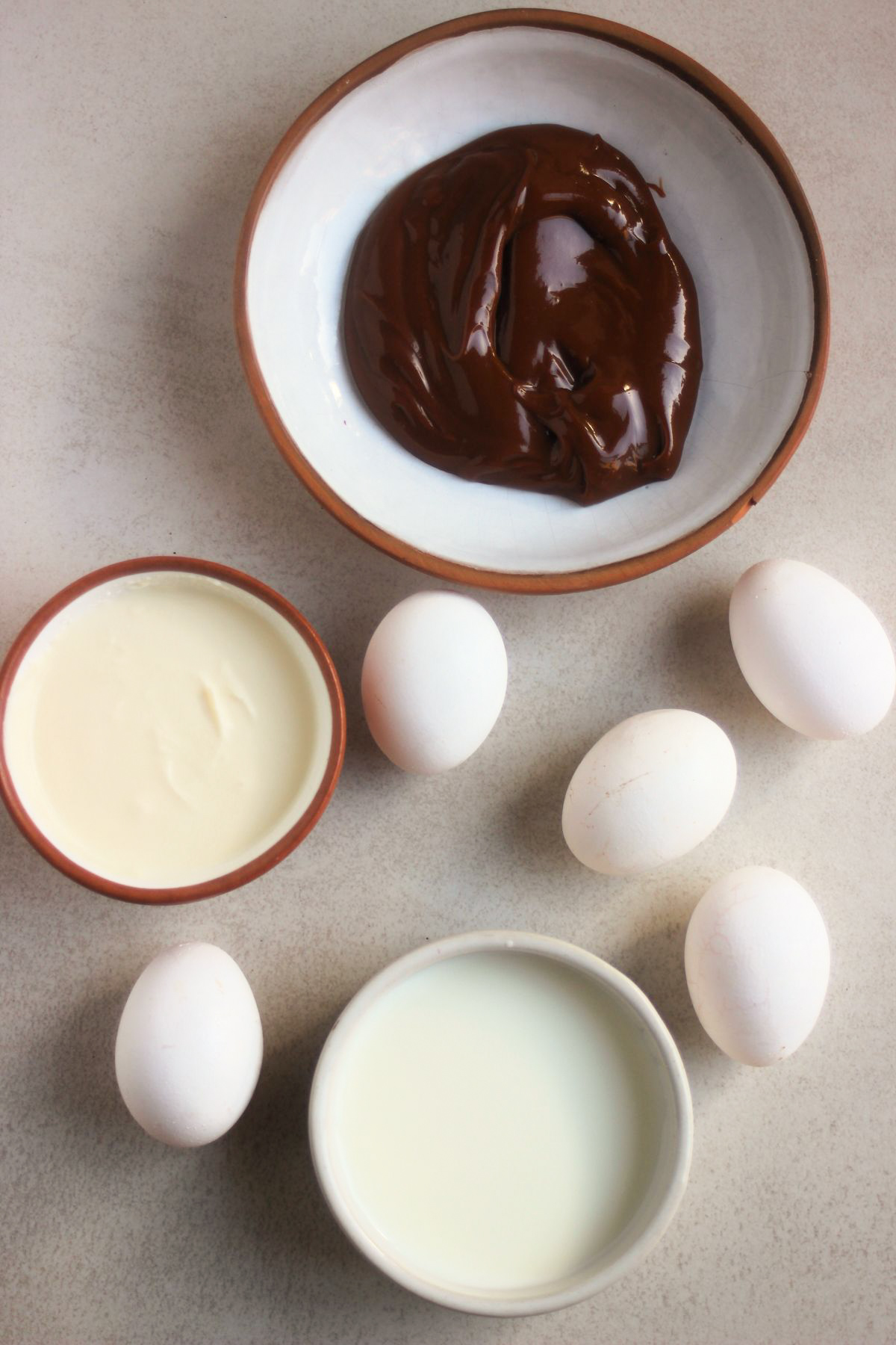 Top view of caramel creme brulee ingredients on a white surface.
